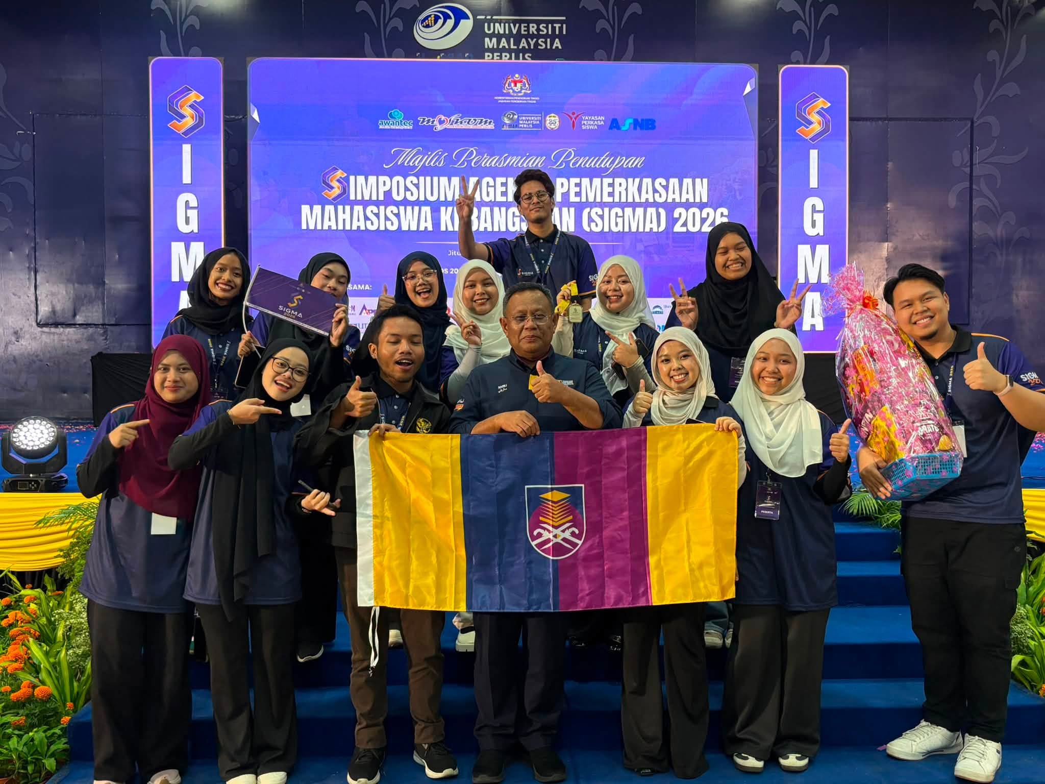Sekumpulan peserta SIGMA 2026 bergambar bersama Timbalan Naib Canselor (Hal Ehwal Pelajar) UiTM, YBrs. Prof. Dr. Haji Mohd Sazili Shahibi, sambil memegang bendera UiTM selepas Majlis Perasmian Penutupan SIGMA 2026 di Universiti Malaysia Perlis (UniMAP).