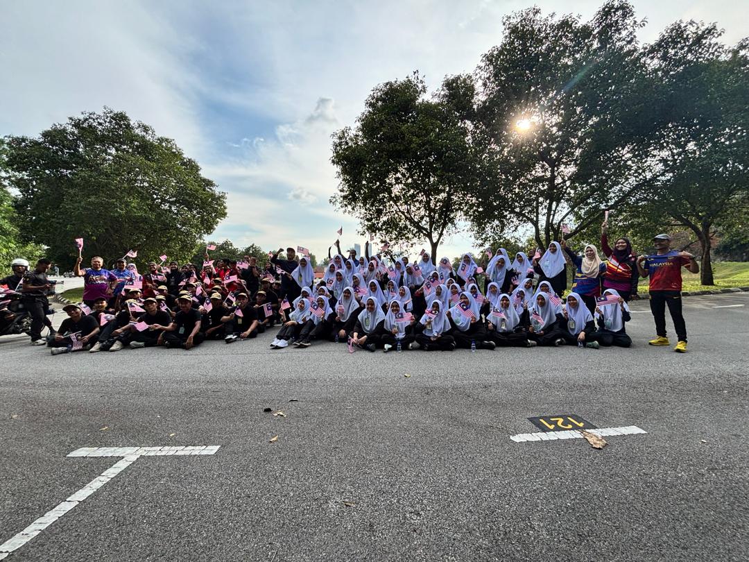 Para peserta bergambar secara berkumpulan di sebuah parking lot.